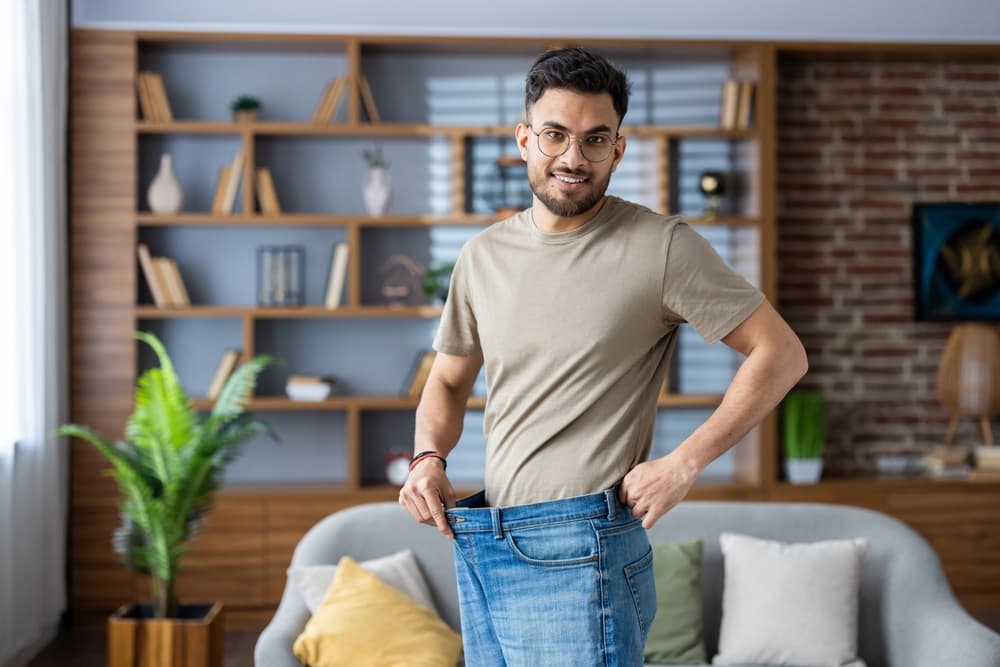 man holding jeans showing weight loss