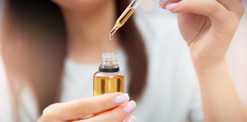 woman holding dropper and oil bottle