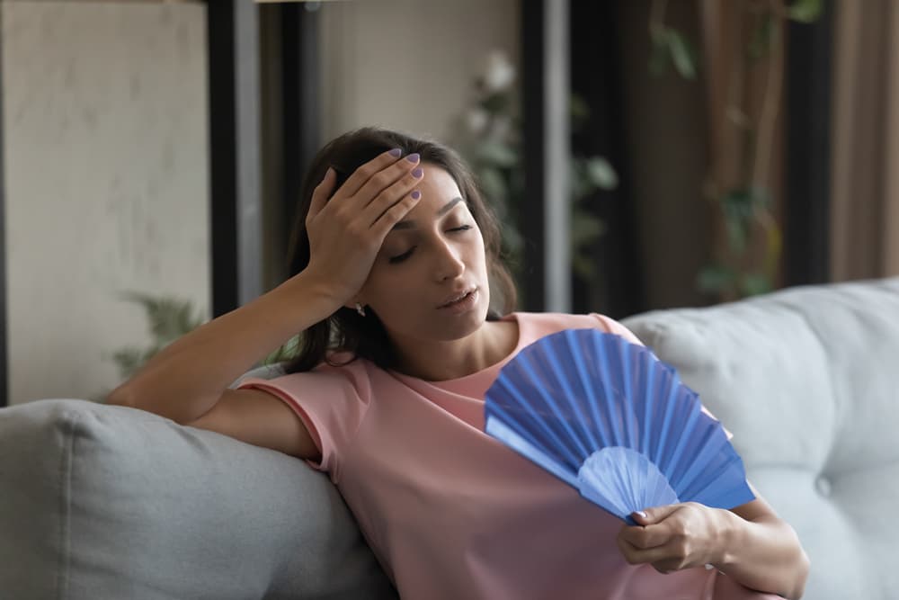 woman holding fan - feeling hot